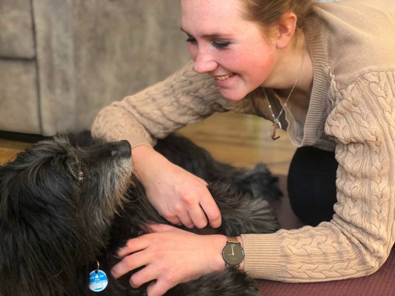 Mai Wölck, erfahrene Tierosteopathin, spielt liebevoll mit einem zufriedenen Hund, der entspannt auf dem Rücken liegt.